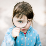 junia pharma - bambina con lente di ingrandimento di fronte all'occhio
