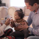 junia pharma - linee guida sullo svezzamento - mamma e papà che danno da mangiare un omogenizzato alla figlia