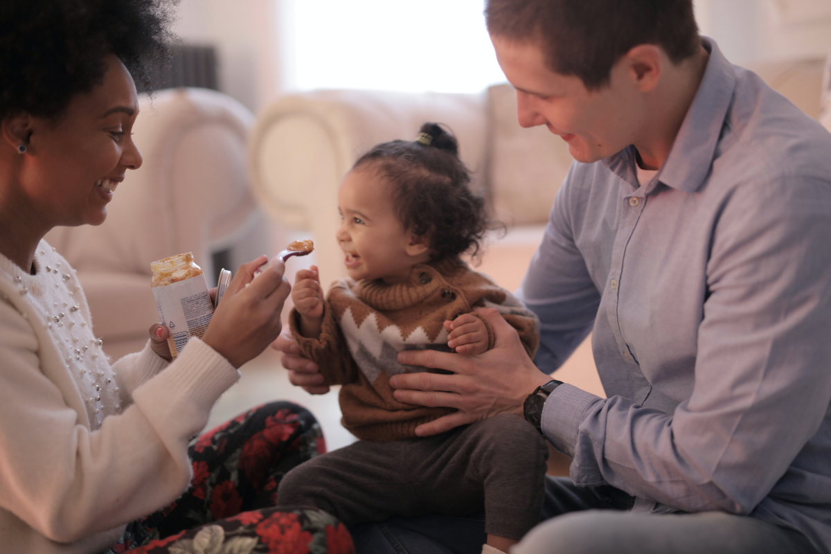 junia pharma - linee guida sullo svezzamento - mamma e papà che danno da mangiare un omogenizzato alla figlia