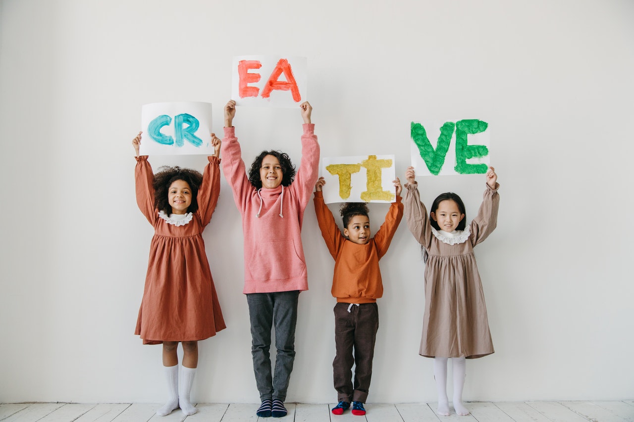 attività creative per bambini da 1 a 6 anni - gruppo di 4 bambini di età diverse con in mano un cartello con scritto "creative"