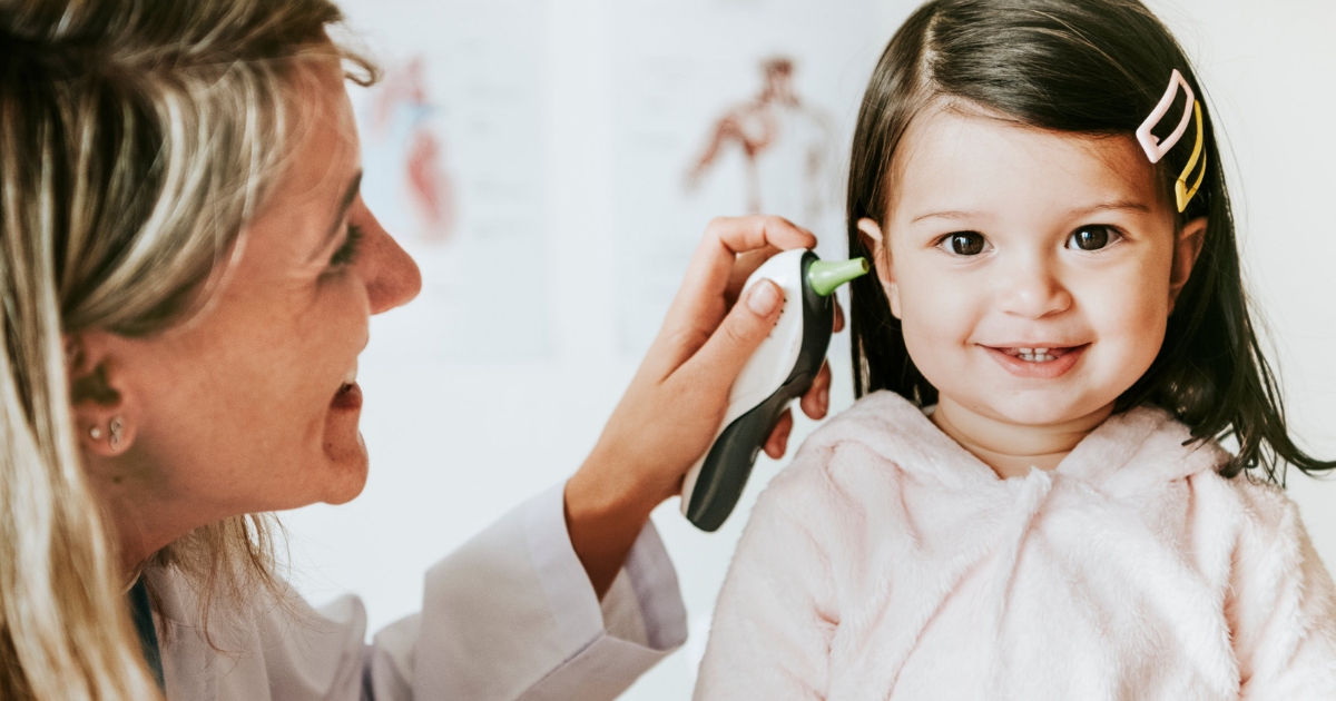 breve guida per pulire le orecchie dei bambini - dottoressa controlla l'orecchio di una bambina sorridente